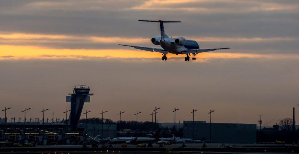 Parken Flughafen Nürnberg : Flugzeug landet am Flughafen Nürnberg bei Sonnenuntergang, Sicht auf den Tower und Parkplätze